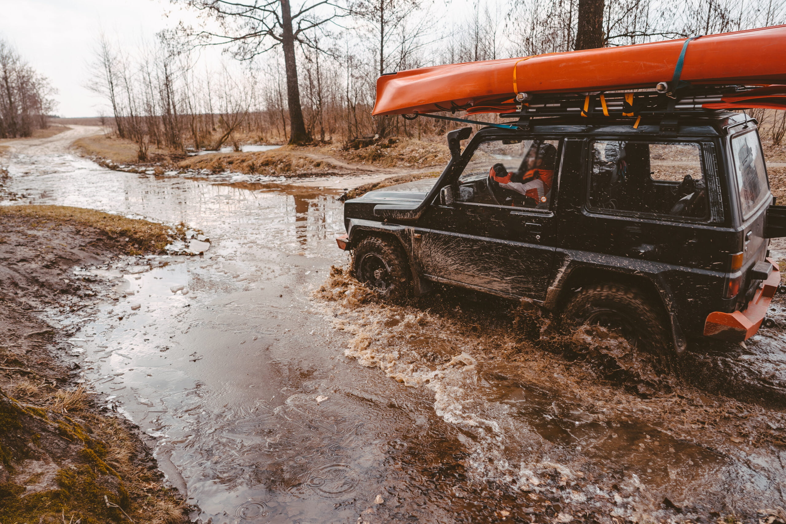 Off-road travel on dirt road road. Mud and water splash in off the road.